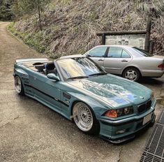 two cars parked next to each other on a dirt road