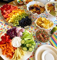 a table topped with plates filled with different types of foods and veggie platters