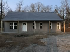 a gray house sitting on top of a dirt field