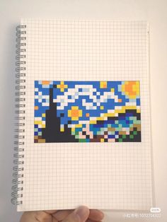 a hand holding up a notebook with the starry night painting on it