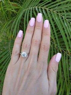 a woman's hand with pink nail polish and a diamond ring