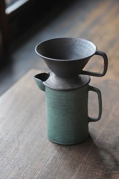 a coffee cup sitting on top of a wooden table next to a window sill