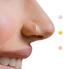 a woman's nose with gold nose piercings on it and dots in the background