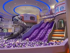 an indoor play area with purple slides and balls