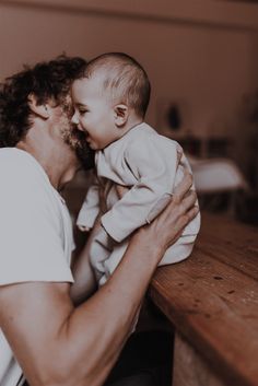 a man holding a baby in his arms and kissing it's face on the cheek