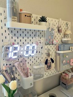 a white desk topped with lots of items and a clock on top of the wall