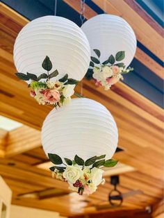 three white paper lanterns with flowers hanging from them