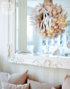 a christmas wreath hanging from the side of a mirror over a couch with pillows on it