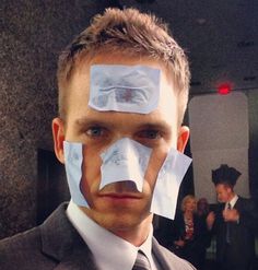 a man with duct tape on his face in front of other people wearing suits and ties