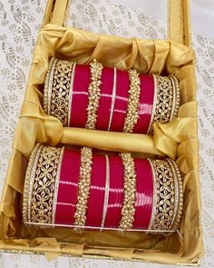 two red and gold bangles in a yellow box on a lace tablecloth covered table