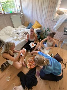 three women sitting on the floor eating pizza