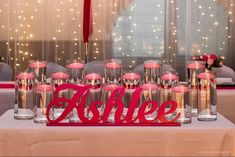 a table topped with lots of pink candles and bottles filled with liquid next to a window