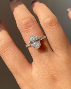 a woman's hand with a diamond ring on top of her finger and the other hand holding an engagement ring