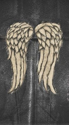 two white wings are on the back of a black leather jacket with zippers and stitching