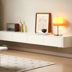 a living room with white furniture and a yellow lamp on the sideboard next to it