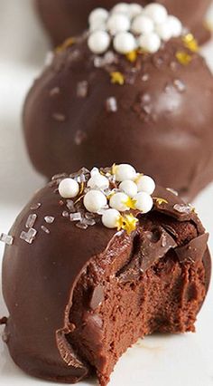 two chocolate covered donuts with white and yellow sprinkles on them sitting on a plate