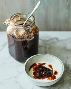 there is a bowl with some food in it next to a glass jar filled with jam