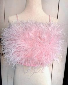 a white mannequin wearing a pink top with feathers on it's chest