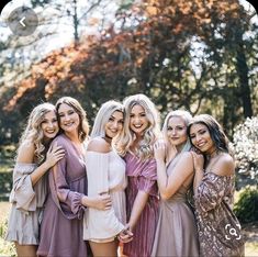 a group of women standing next to each other posing for a photo in front of trees