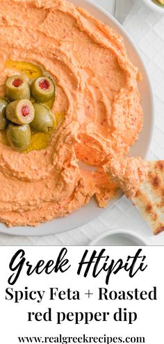 a bowl of greek hummus with olives and pita bread on the side