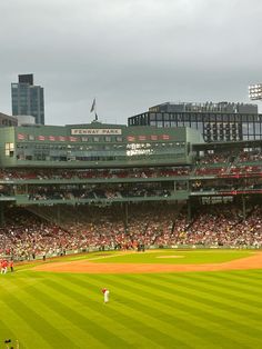 a baseball stadium filled with lots of people on top of a green grass covered field