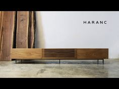 a wooden cabinet sitting on top of a floor next to a wall with the word haranc written above it