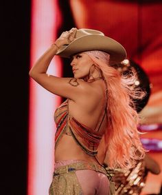 a woman with long pink hair wearing a cowboy hat and bra - revealing her breast