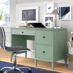 a green desk and chair in a room with pictures on the wall above it, next to a blue rug