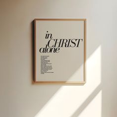 a framed poster hanging on the wall in front of a window that reads in christ alone