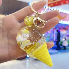 a hand holding a yellow ice cream cone keychain