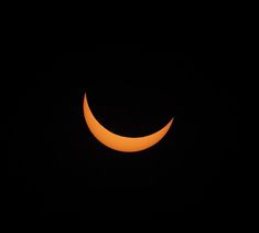 the moon is seen in front of an orange crescent during a partial solar eclipse on friday