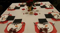 the table is set for christmas dinner with snowman plates and napkins on it