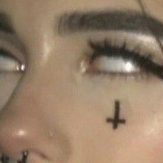 a woman's face with cross tattoo on her nose