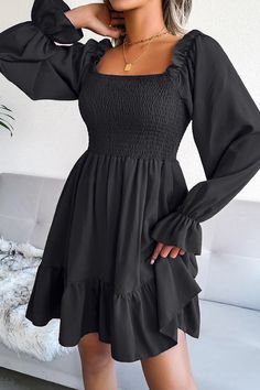 a woman wearing a black dress with long sleeves and ruffled heming on the shoulders