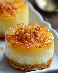 two desserts on a white plate topped with pineapple sauce and coconut flakes