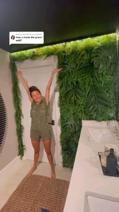 a woman standing in front of a bathroom with plants growing on the wall behind her