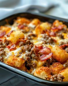 a casserole dish with sausage, cheese and bacon on top is ready to be eaten