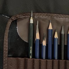 six pencils in a leather case on a table