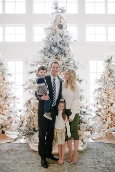 a family poses in front of a christmas tree