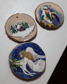 three painted plates sitting on top of a white table next to each other and one is holding a christmas tree