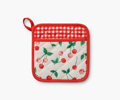 an oven mitt with cherries and gingham print on it, hanging from the side