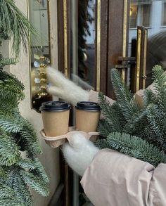 two cups of coffee are being held up by someone's hand in front of a door