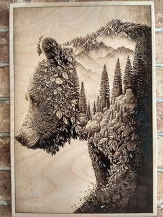 a drawing of a bear with trees and mountains in the background on a wooden plaque