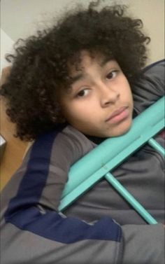 a young boy with curly hair sitting in a chair