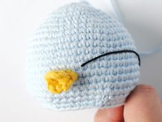 a crocheted blue hat with a yellow flower on the side and a black cord