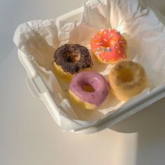 four different flavored donuts in a take out container on a table top,