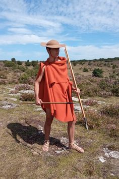 a man in an orange dress and hat holding a stick