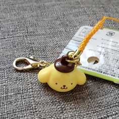 a keychain with a small yellow bear on it's side and a tag attached to it