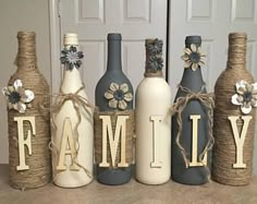 four wine bottles are decorated with flowers and the word family is spelled out in front of them