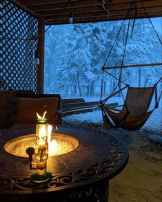 a lit candle sitting on top of a table in front of a hammock